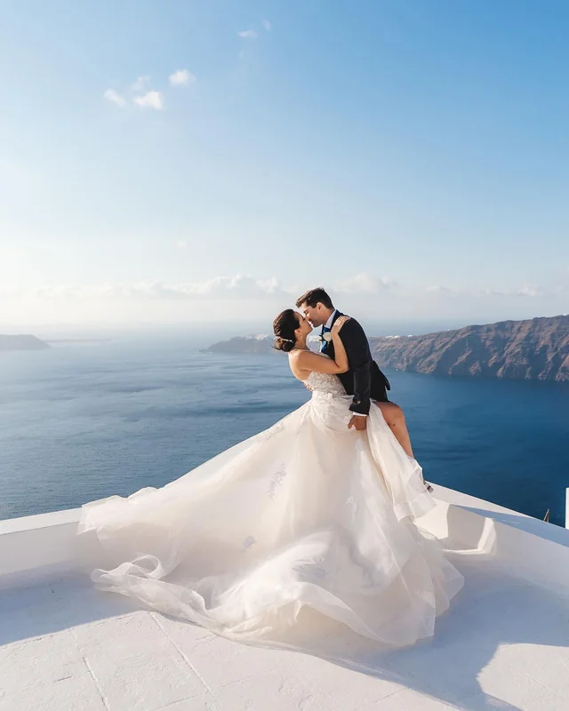 Bride standing by blue dome in Santorini – winter sun wedding location