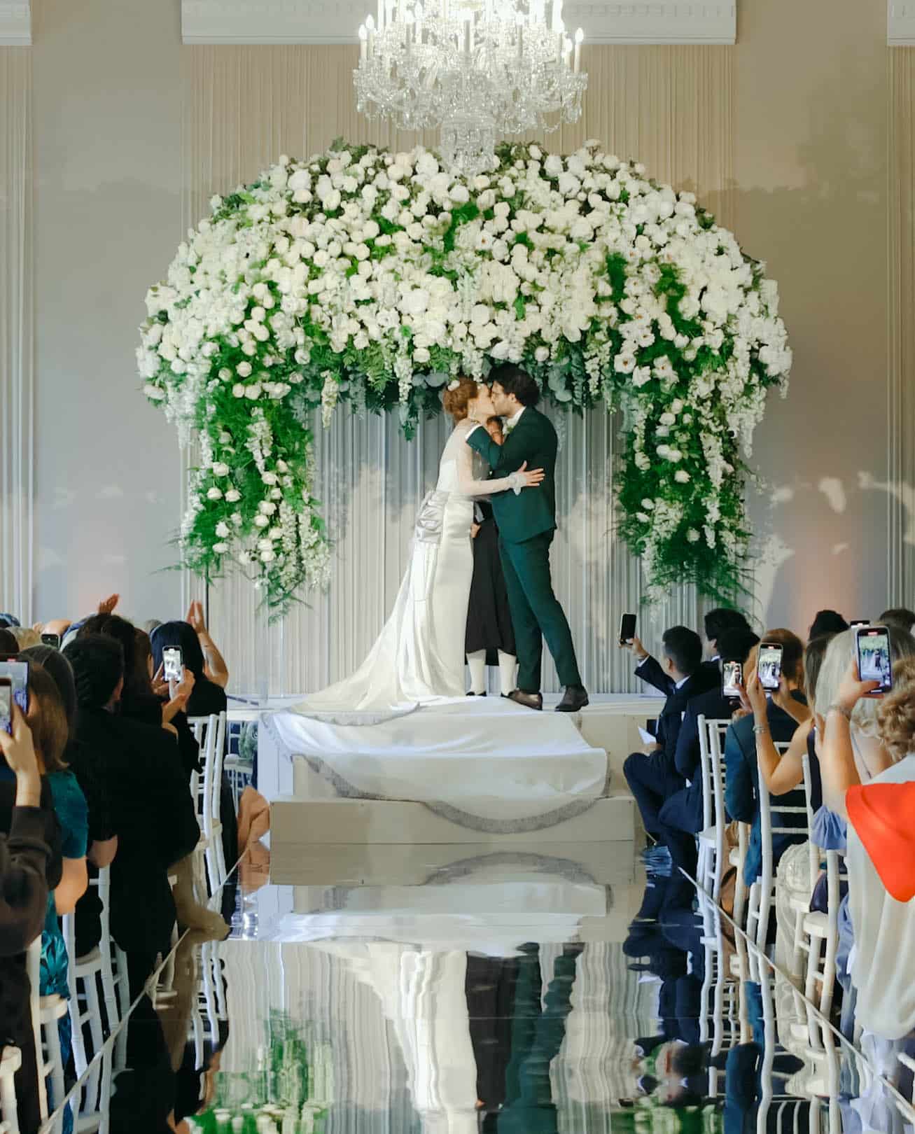 Bride and groom first kiss at Hopetoun House wedding ceremony Scotland with white floral arch — photography by Matt Porteous